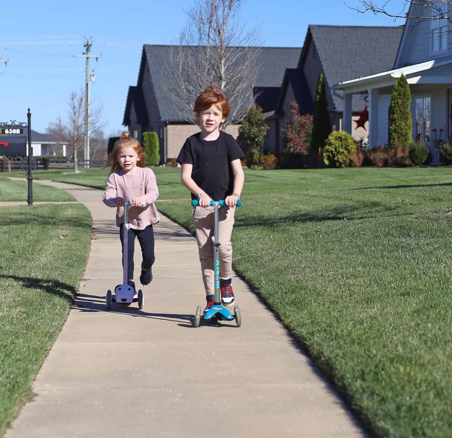 Two kids riding scooters